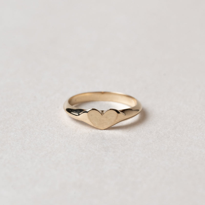 Gold ring with heart design on a light gray background