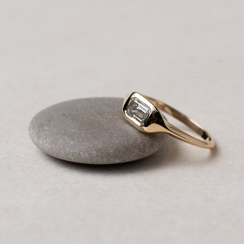 Gold ring with a diamond on a gray stone surface