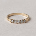 Gold ring with small diamonds on a light gray background