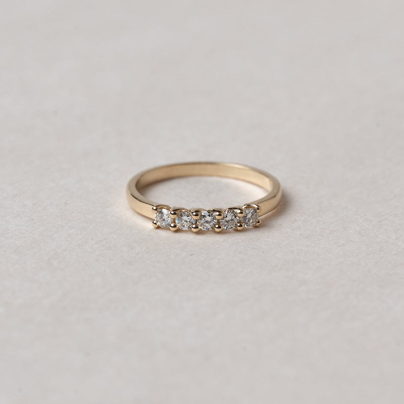 Gold ring with small diamonds on a light gray background