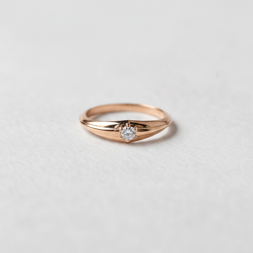 Rose gold ring with a diamond on a light gray background