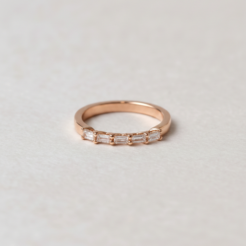 Rose gold ring with small diamonds on a light gray background